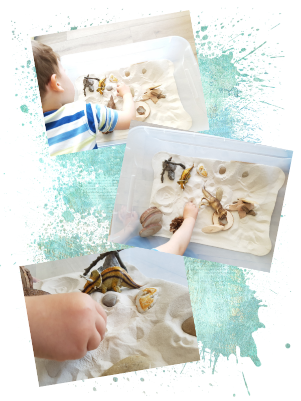 Kind spielt mit Sand, Holz und Dinos in einer transparenten Kiste